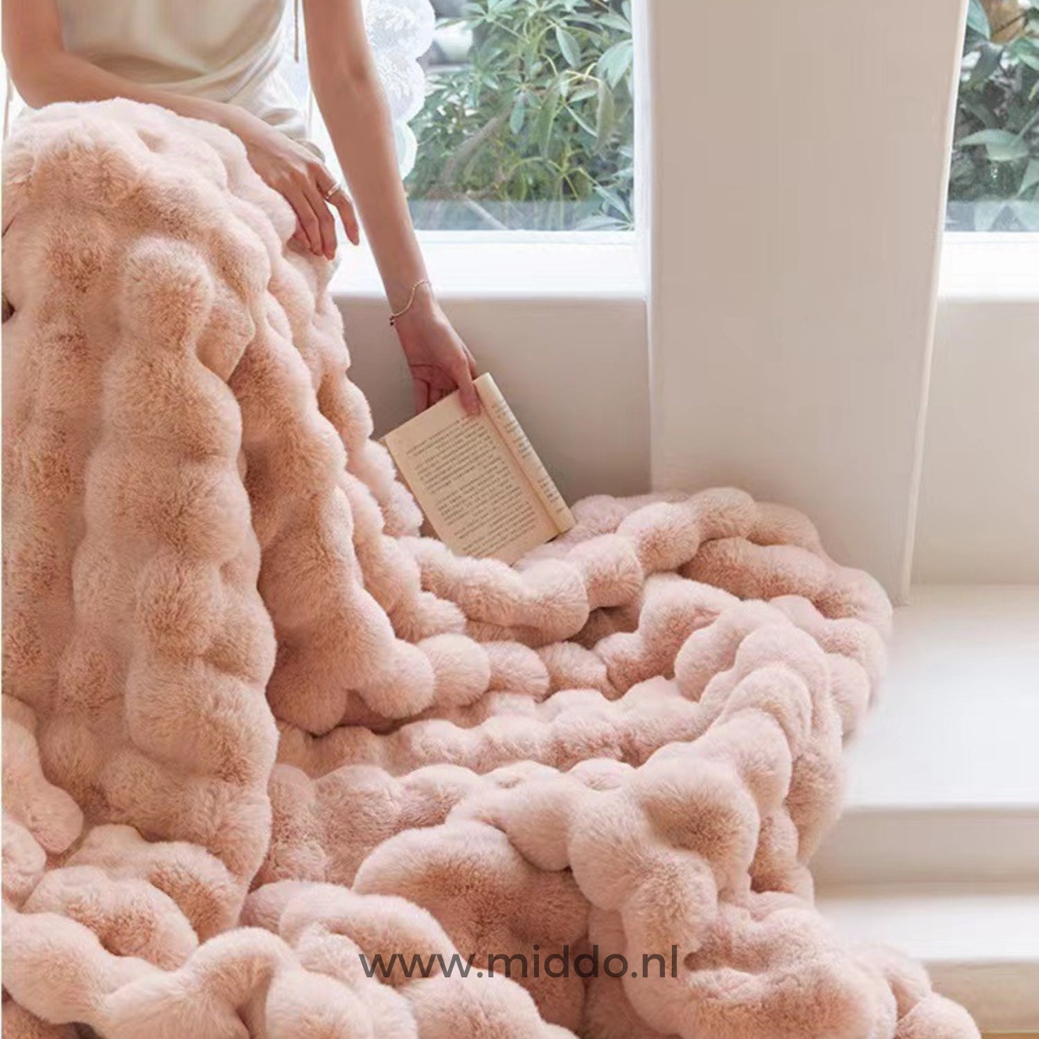 Roze fluffy deken over bank vrouw leest boek