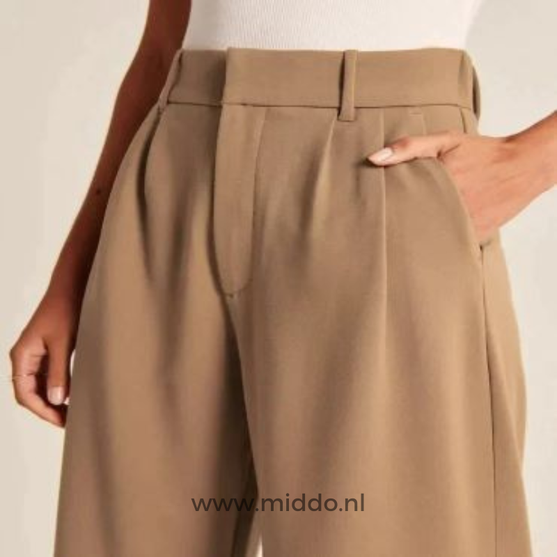 foto van vrouw in bruine wijde pantalon gezien vanaf de middel en heeft haar hand in de steekzak.