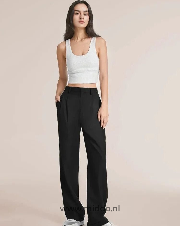 Een slanke dame showt de zwarte wijde pantalon met een wit hemdje er boven