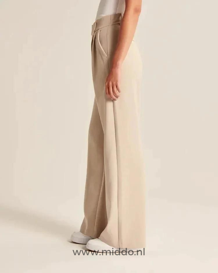 Vrouw met witte schoenen showt de wijde pantalon beige vanaf de zijkan