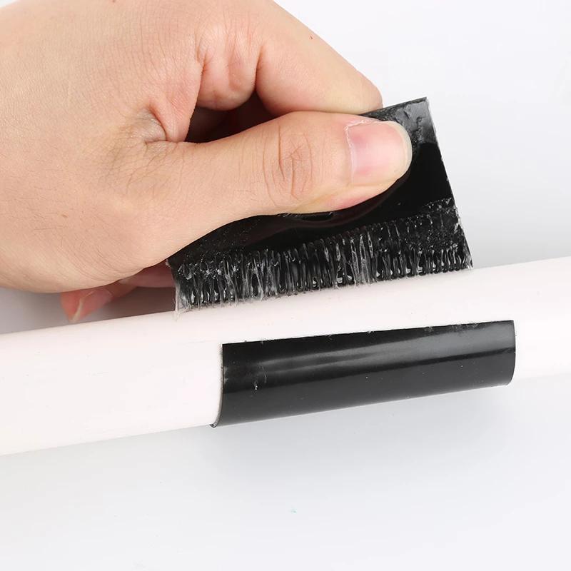 Hand die zwarte watervaste tape op een pijp aanbrengt.