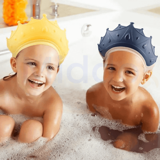 Twee lachende kinderen in bad met gele en blauwe kroonvormige badhoeden.