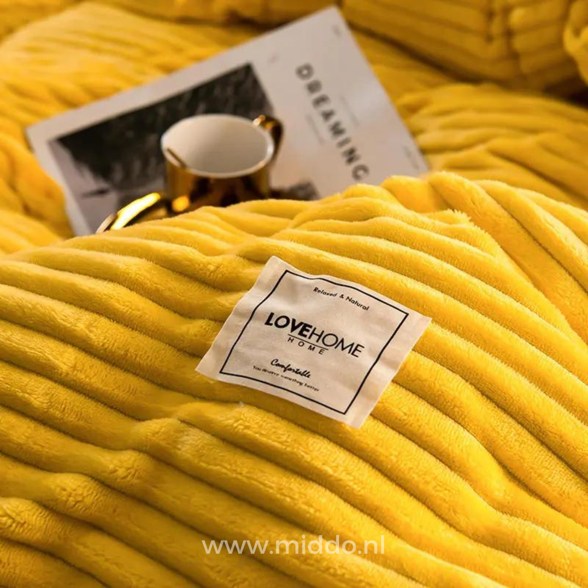 Close-up van geel dekbedovertrek met een kopje en tijdschrift